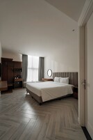 Habitación de hotel moderna con una cama grande, un armario, un escritorio y una ventana con cortinas.
