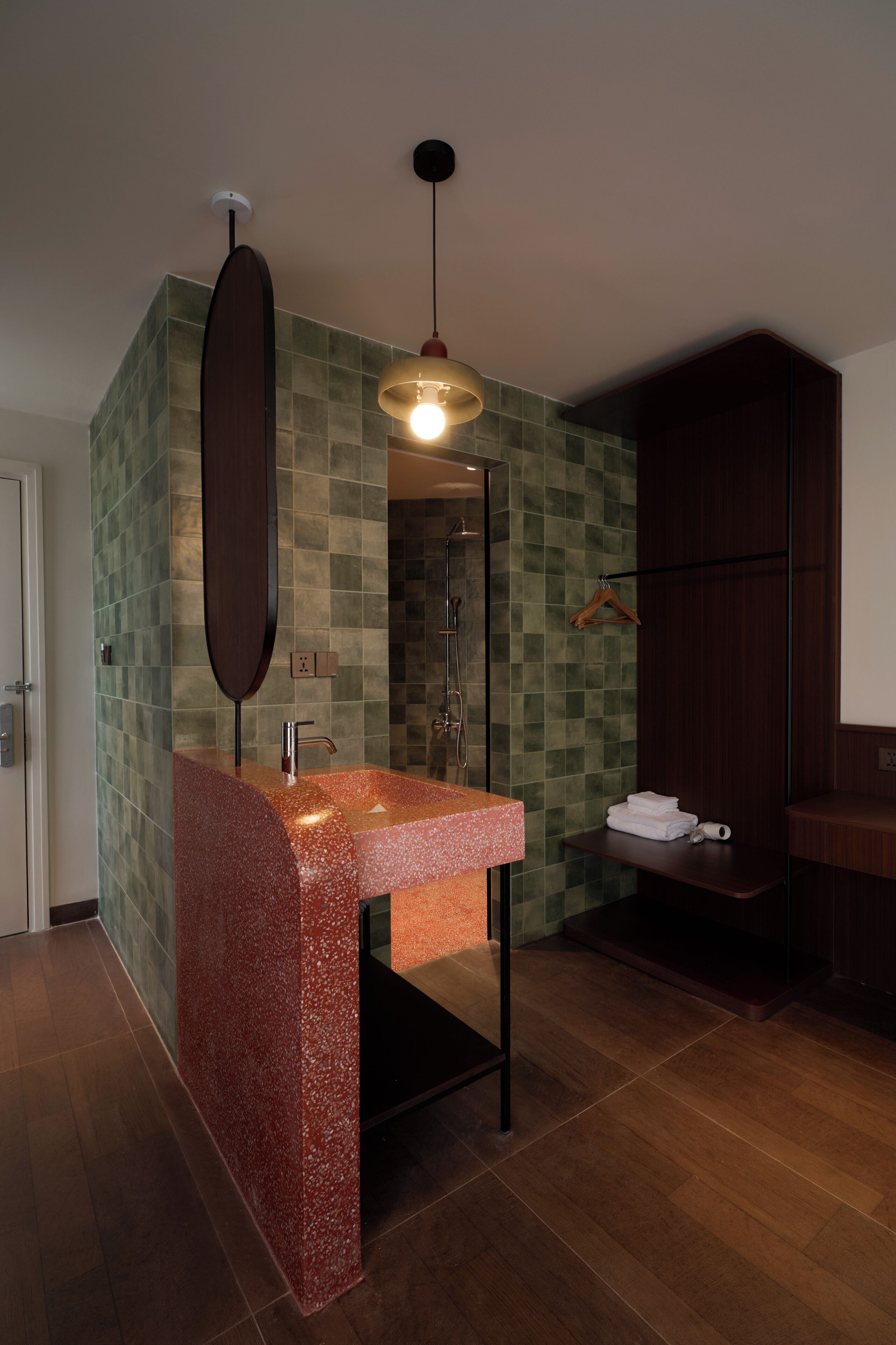 A modern bathroom with a granite countertop, a towel rack, and a hanging light fixture.