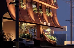 Un hotel moderno con fachada curva, plantas exteriores y una escalera visible que lleva a la entrada.