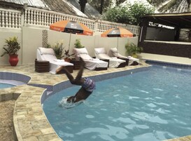Una piscina con sillones de descanso y sombrillas.