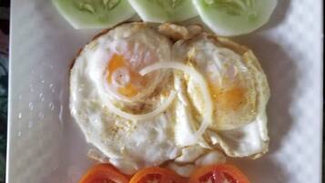Um prato com ovo frito, fatias de pepino e fatias de tomate.