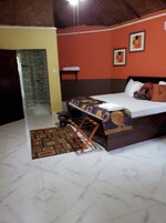 Un dormitorio con cama, una mesita, una silla, un tapete estampado y zona de ducha.