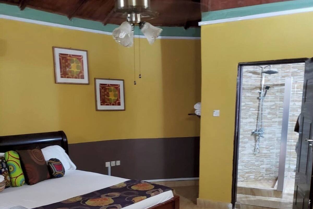 Une chambre d’hôtel avec un lit, un espace douche et un tapis à motifs floraux.