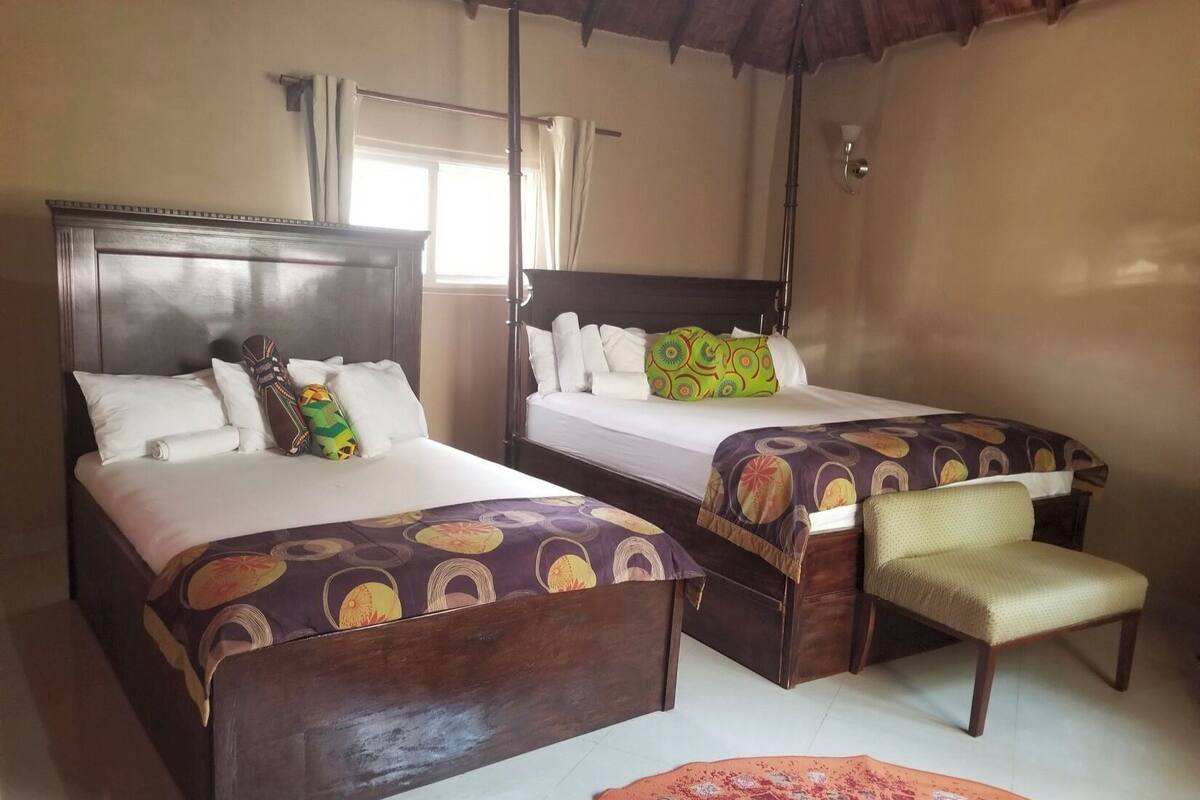 Une chambre d’hôtel avec deux lits, un banc et un tapis rouge.