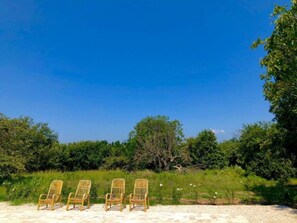 Una spiaggia con quattro sedie in vimini disposte una accanto all'altra, rivolte verso il mare.