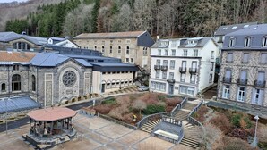 Un edificio histórico con un patio central, arquitectura de piedra y un pequeño pabellón.