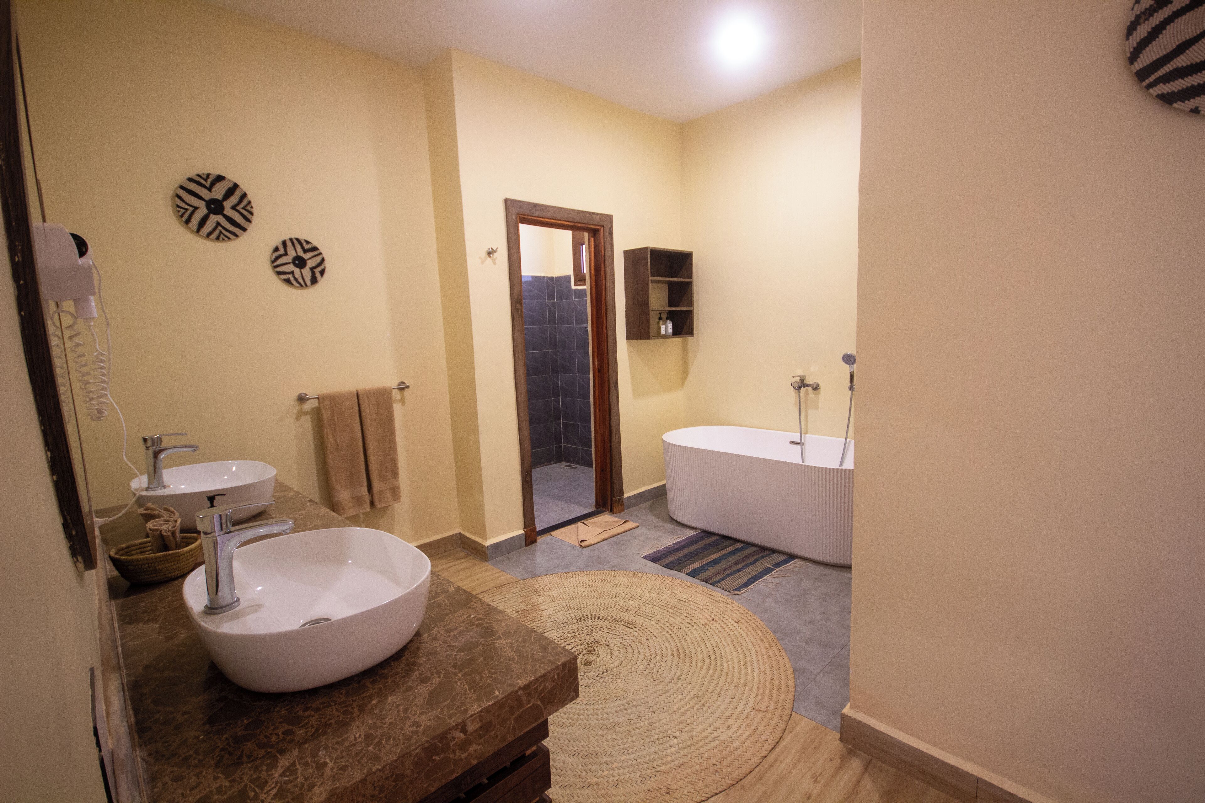 A bathroom with a large white sink, a bathtub, and a mirror. There is a towel rack and a shelf with toiletries.