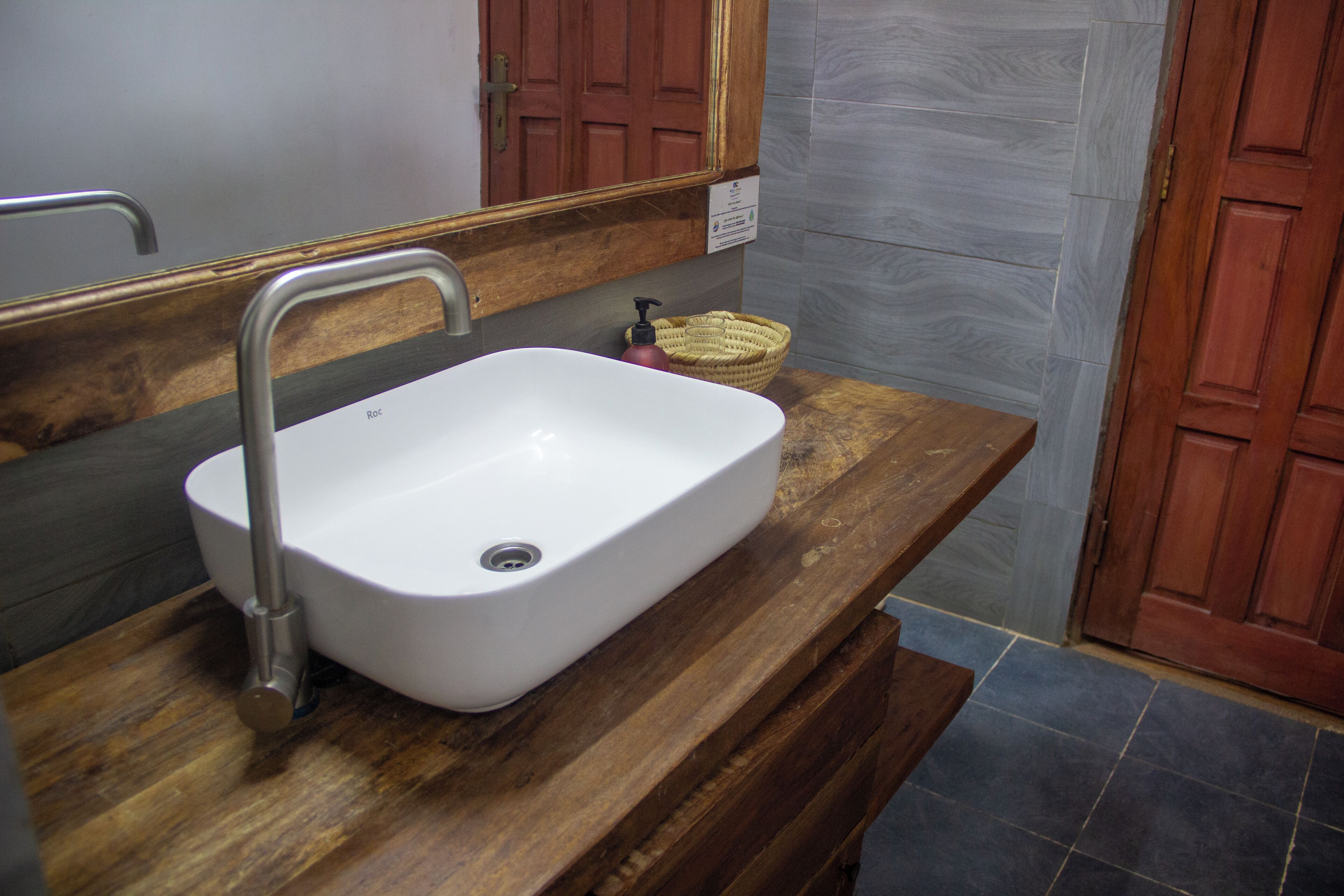 Un bagno con un lavandino bianco, un piano in legno e uno specchio.