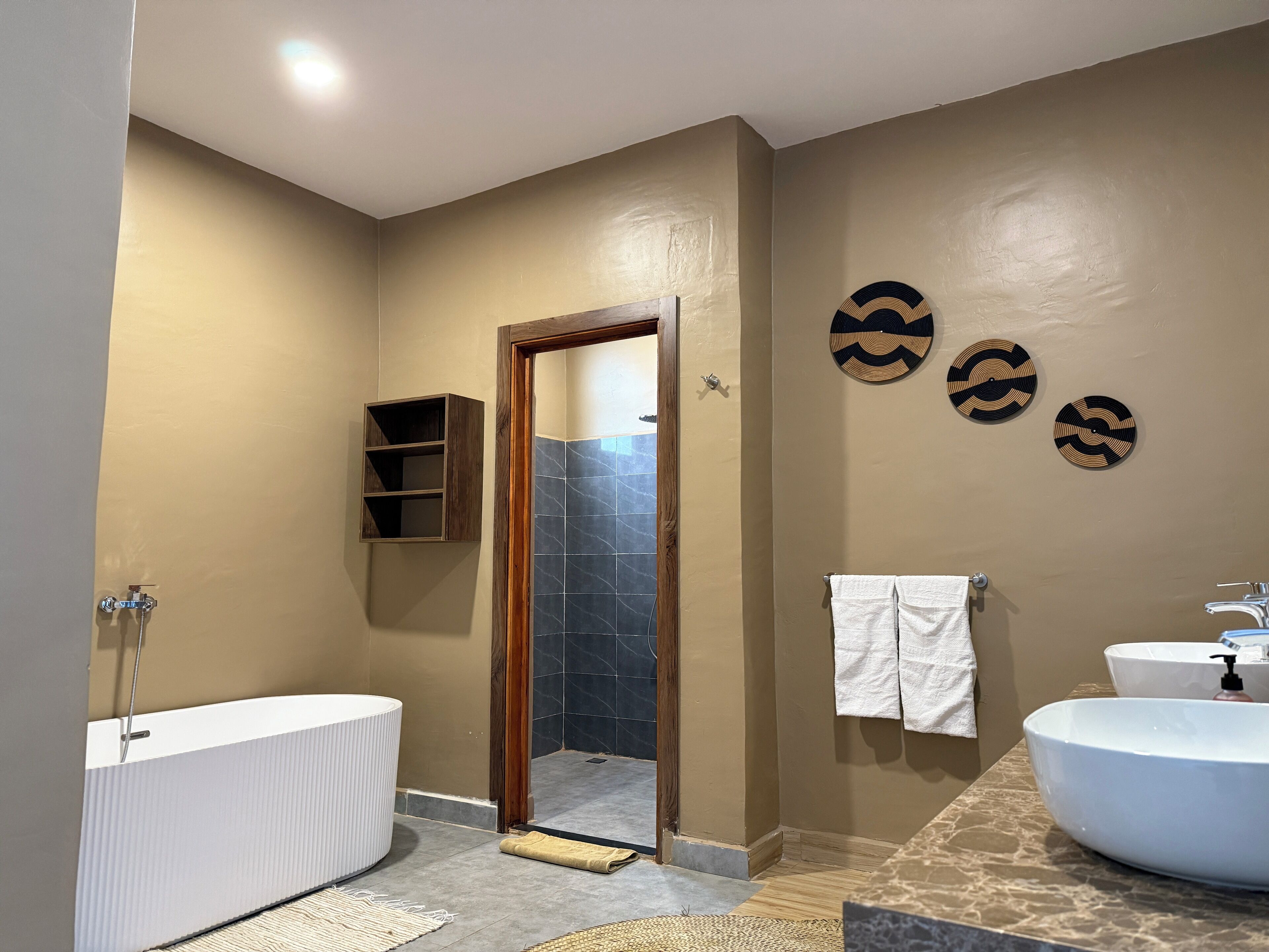 A bathroom with a bathtub, two sinks, a towel rack, and decorative wall art.