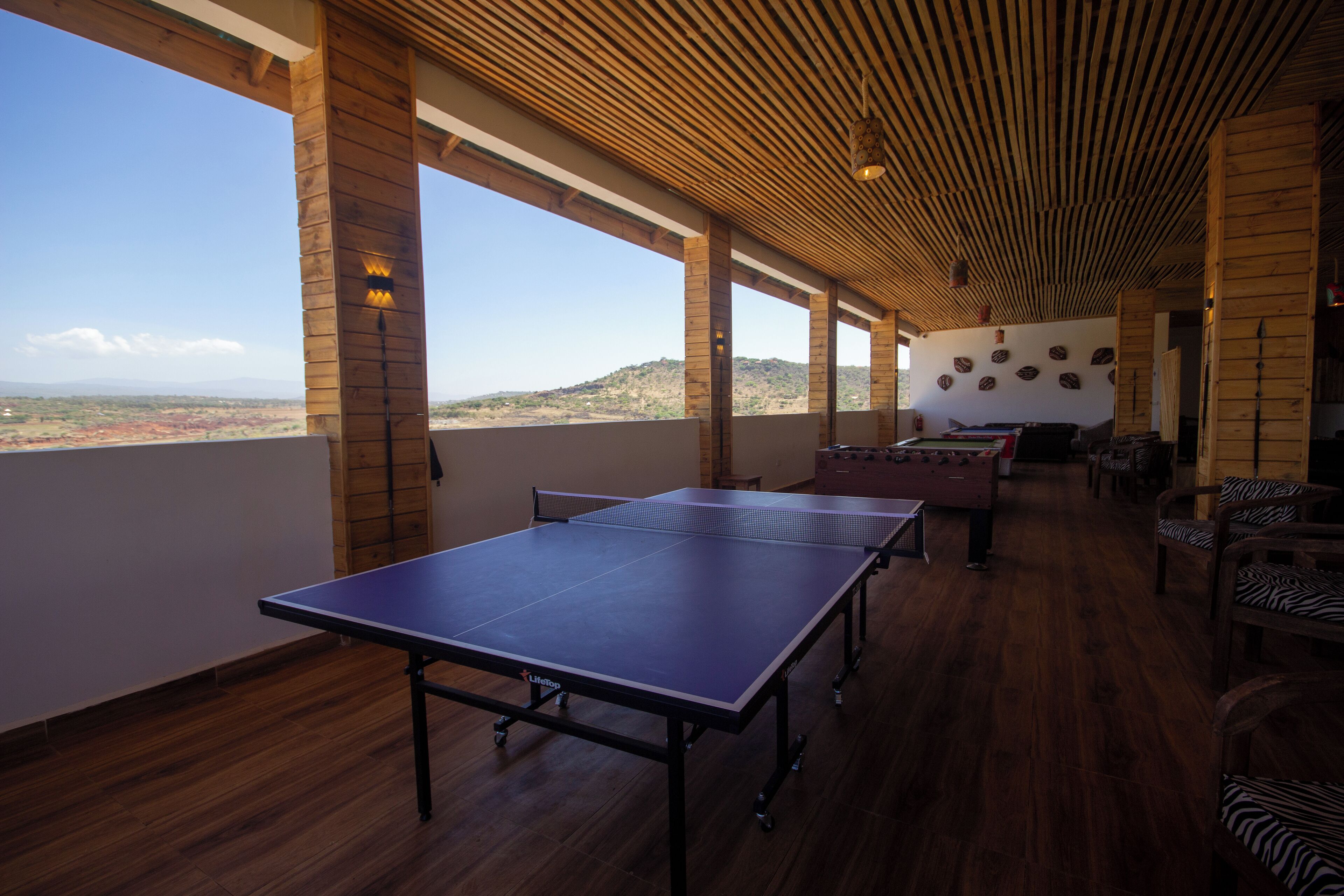 A ping pong table in a room with wooden floors and large windows.