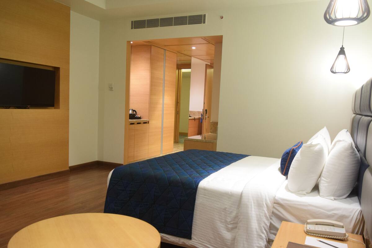 Une chambre d’hôtel équipée d’un lit, d’un bureau, d’une chaise, d’une télévision et d’une kitchenette.
