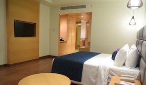 Een hotelkamer met een bed, een bureau, een stoel, een televisie en een kitchenette.