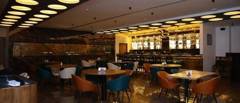 A modern restaurant with a bar area, multiple seating options, and a polished floor.
