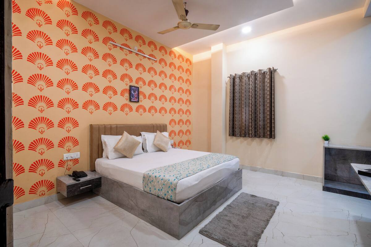 A bedroom with a bed, a bedside table, a nightstand, a ceiling fan, and a patterned wall.