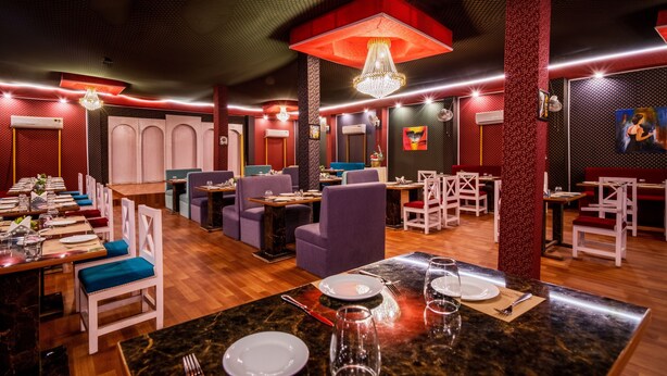 A restaurant with multiple dining areas, including a long communal table and several smaller tables. - Hotel Chotiwala – 10 Mins from Kashi Vishwanath Temple (Varanasi)
