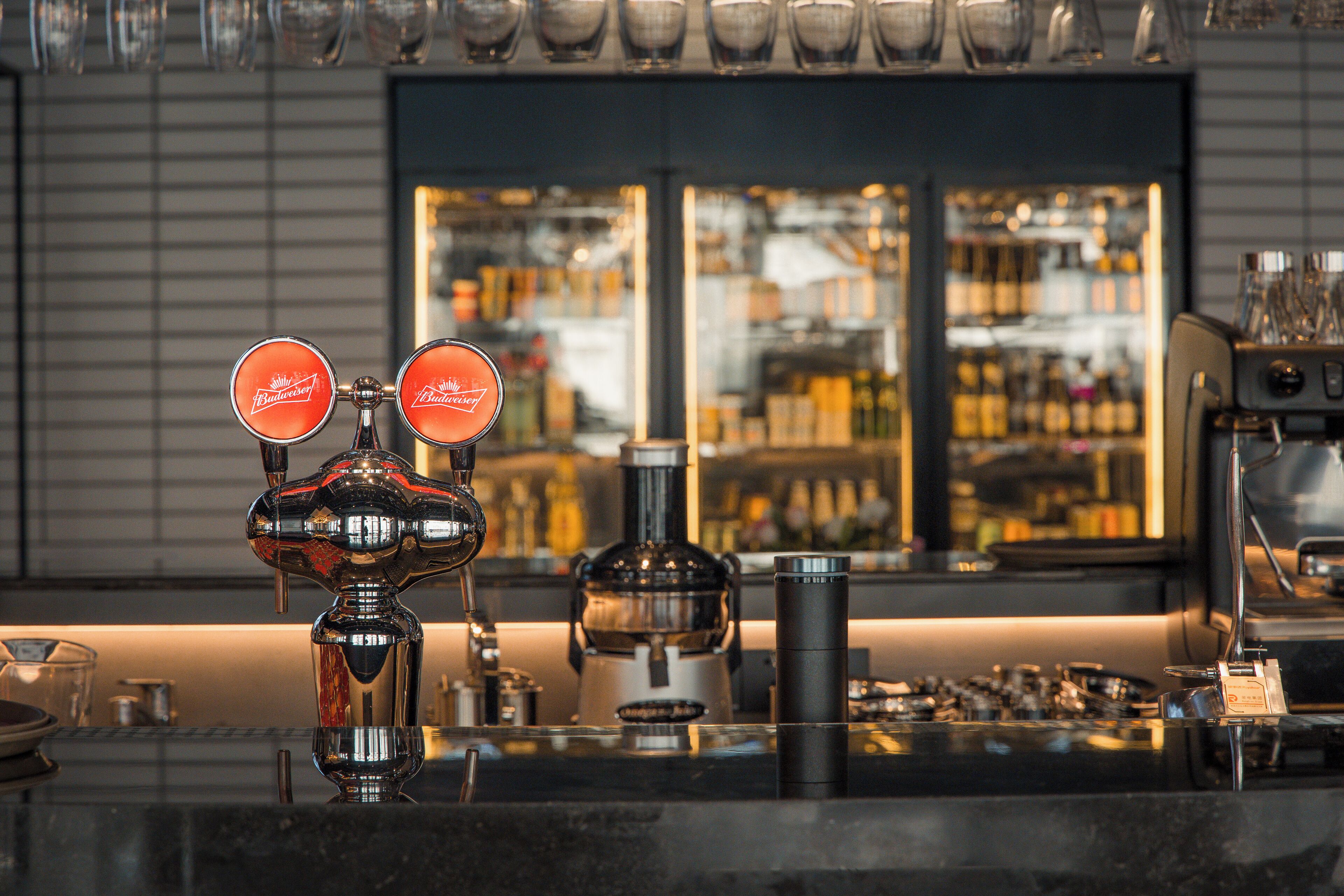 Una zona de bar con mostrador, una máquina de café y una exhibición de botellas al fondo.