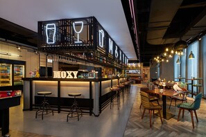 Una zona de bar con un letrero de neón, taburetes y una sala de comedor con sillas y mesas.