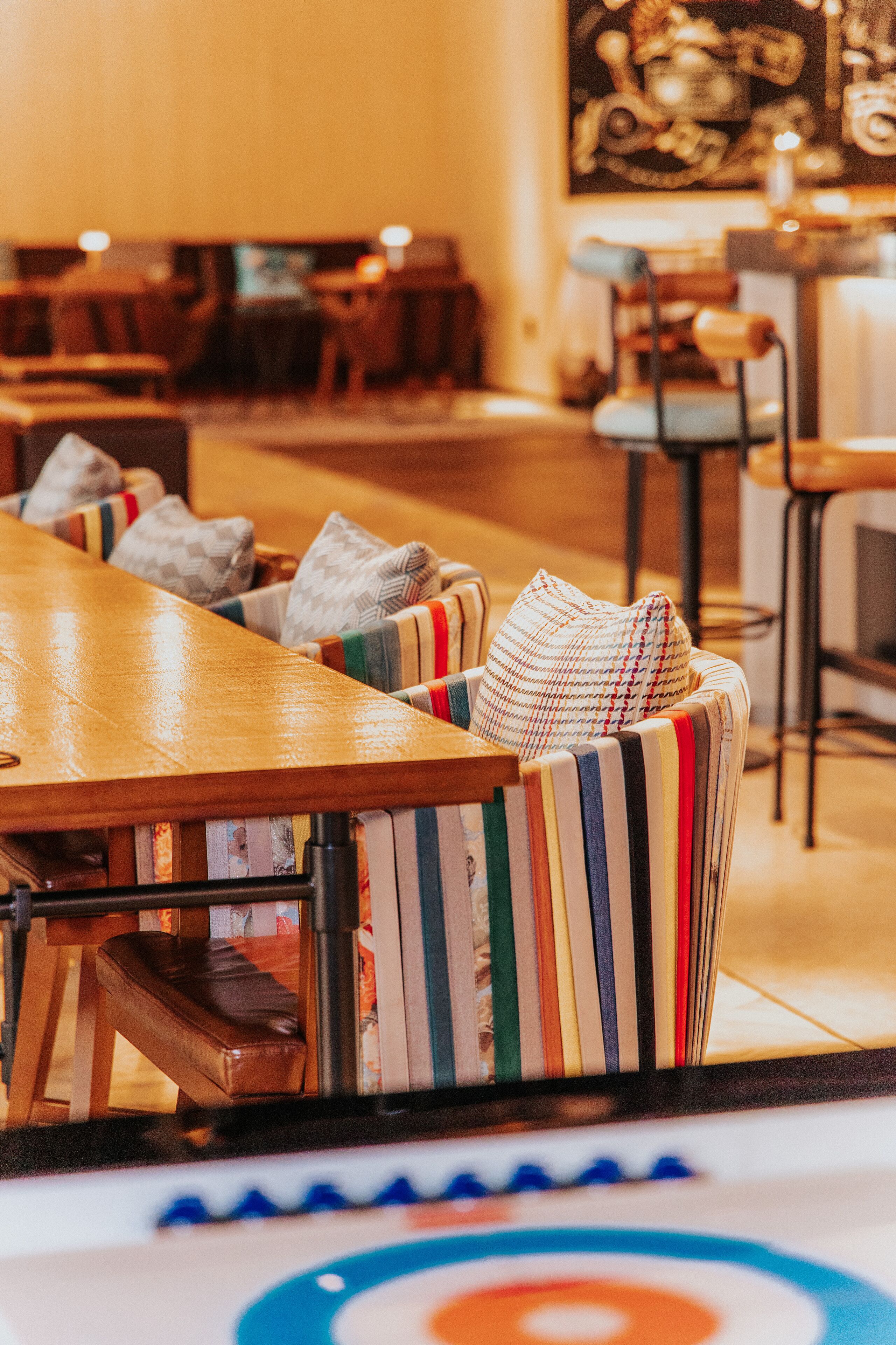A restaurant with striped upholstered chairs, a wooden table, and a patterned floor.