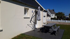 Ett hus med en uteplats, ett bord och ett parasoll.