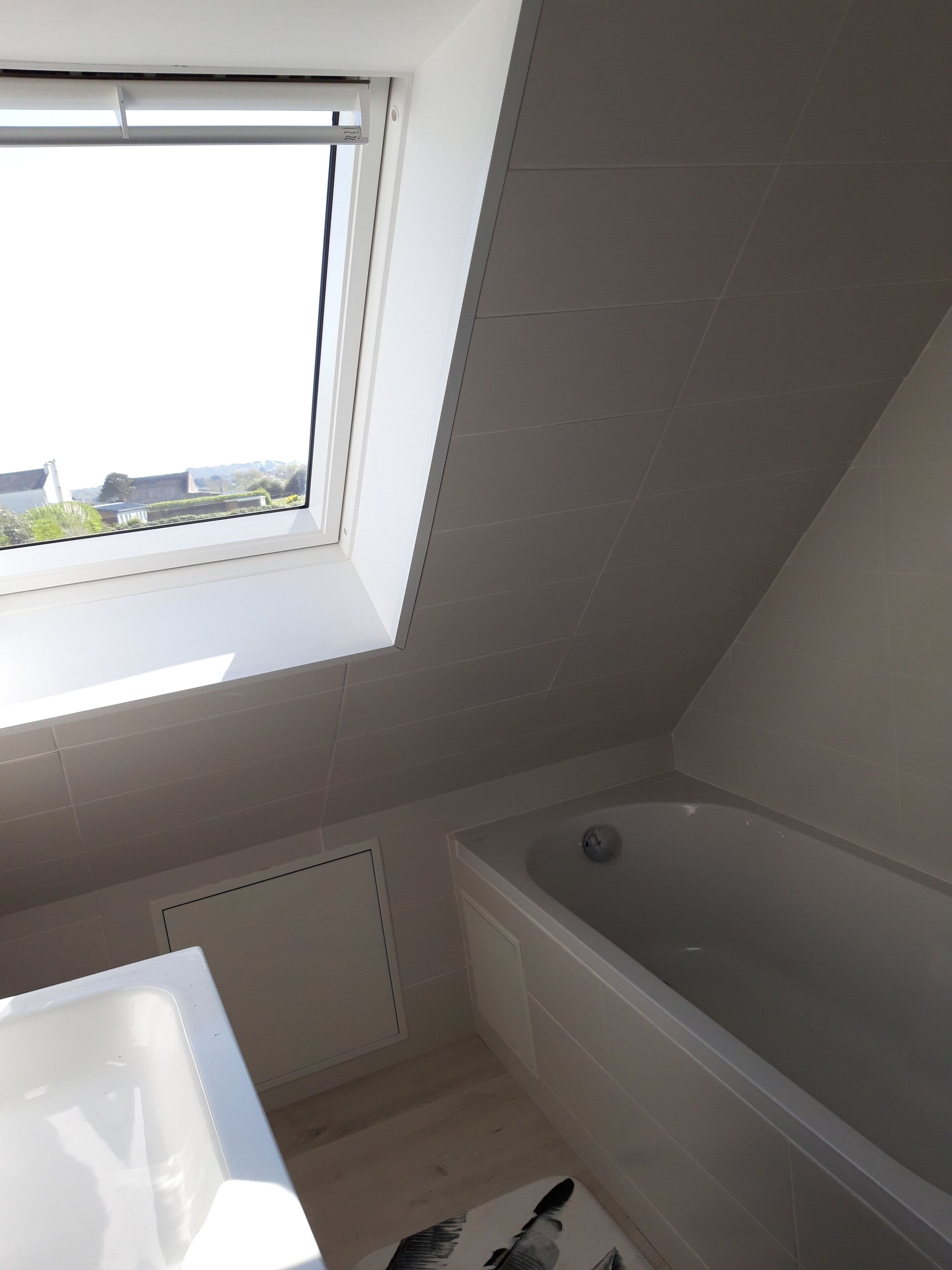 Ein Badezimmer mit Dachfenster, Badewanne und einem weißen Waschbecken.