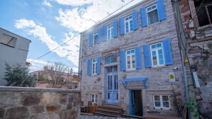 A stone building with blue shutters and a wooden door. - Cunda Alesta Otel (Ayvalik)