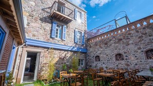 A stone building with a courtyard featuring outdoor seating. - Cunda Alesta Otel (Ayvalik)