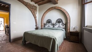 Une chambre à coucher avec un lit, une table de chevet, une lampe et un mur en briques en forme d’arc.