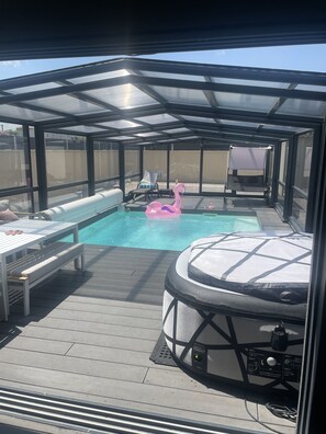 A covered outdoor pool area with lounge chairs, a hot tub, and a flamingo float. - Romantic lodging with a heated indoor pool, sauna, spa, and rooftop kitchen (Carpentras)