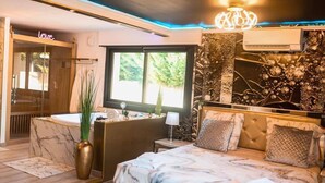 Une chambre moderne avec un grand lit, une coiffeuse avec un miroir, une baignoire et une fenêtre donnant sur un paysage verdoyant.