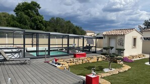 Un espace extérieur abrité comprenant une piscine, des chaises longues et un coin salon.