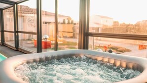 Un bain à remous avec vue sur un quartier résidentiel, grâce à de grandes fenêtres.