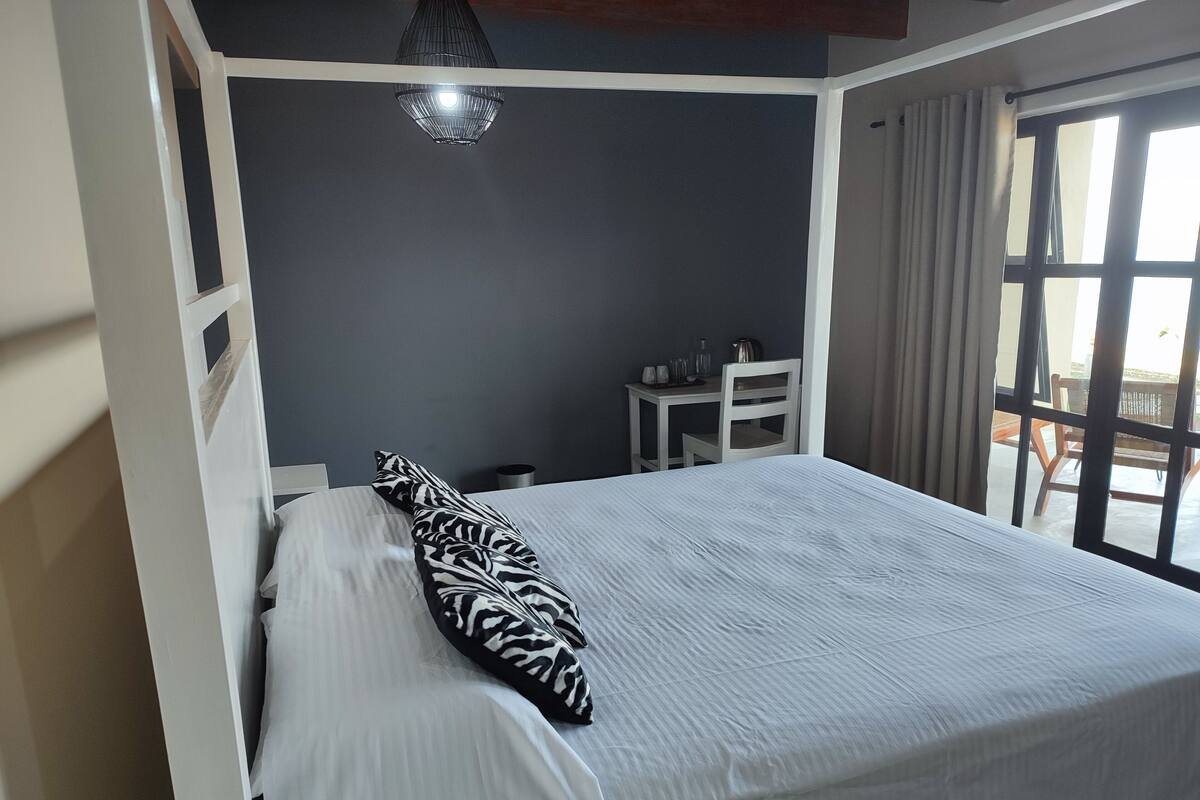 A bedroom with a bed, a desk, and a window.