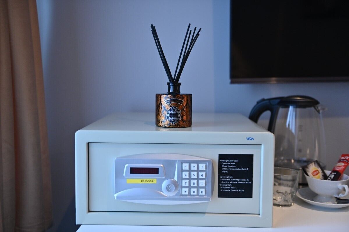 A minibar with a minibar fridge, a glass of water, and a cup with a spoon.