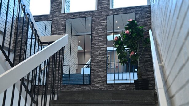 A modern building with a staircase, large windows, and a potted plant. - Älvsjö stadshotell (Arsta)