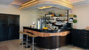 A bar area with a curved counter, bar stools, and shelves stocked with bottles. - Restauracja Hotel Imperial (Jaslo)
