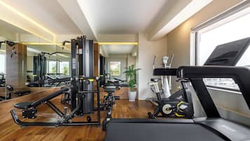 A modern gym with cardio equipment, weight machines, and a large mirror.