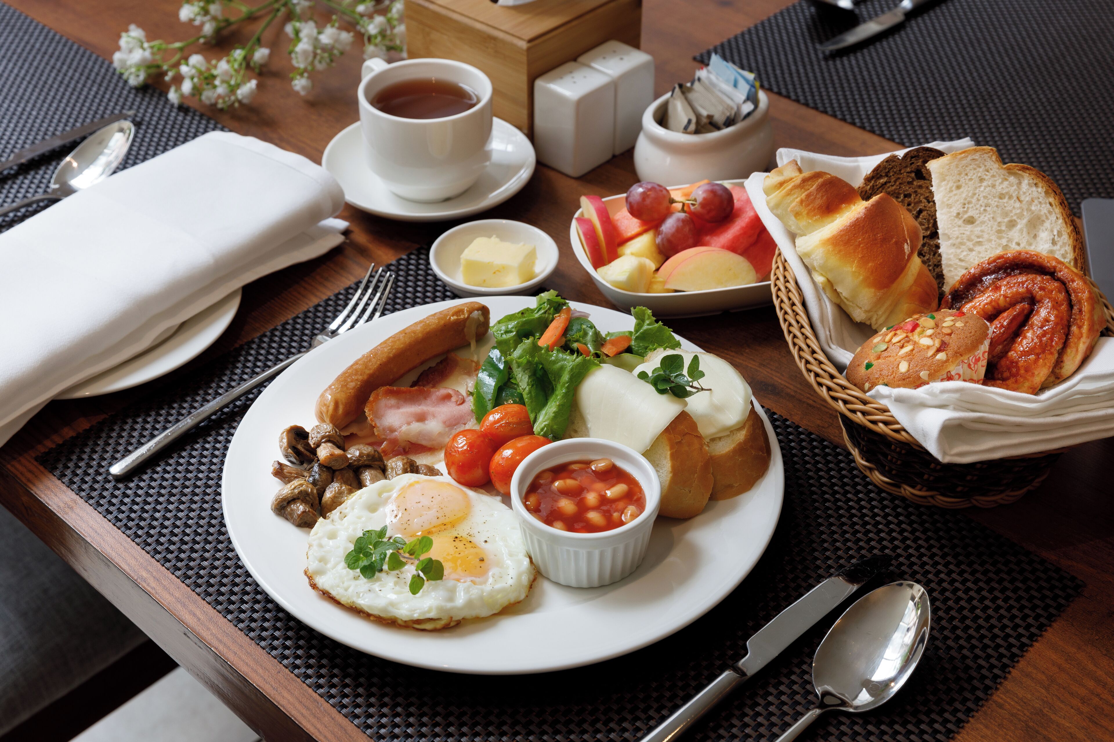 A breakfast tray with eggs, mushrooms, tomatoes, and bread.