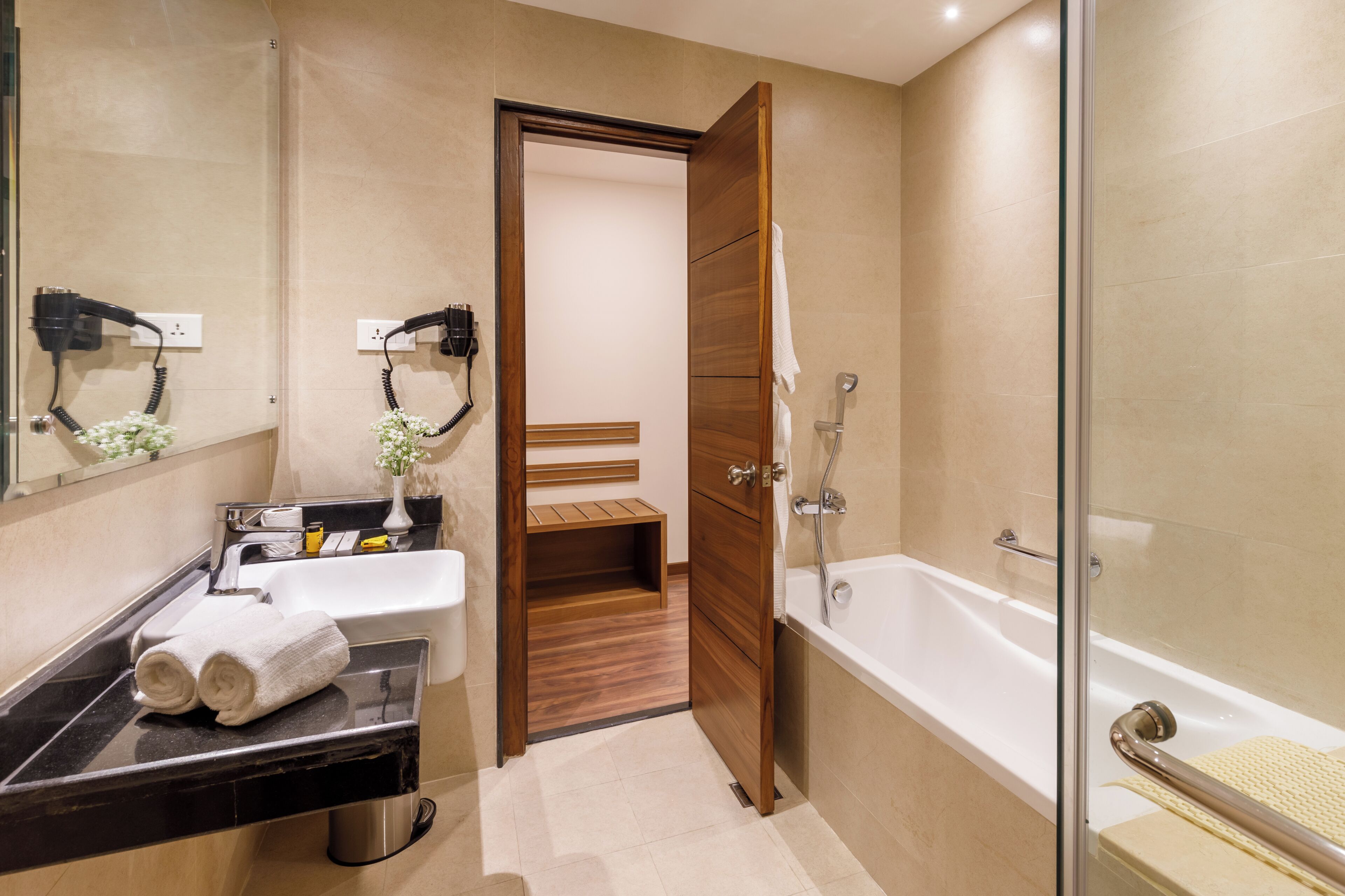 A modern bathroom with a sink, mirror, towel rack, and a glass-enclosed shower area.