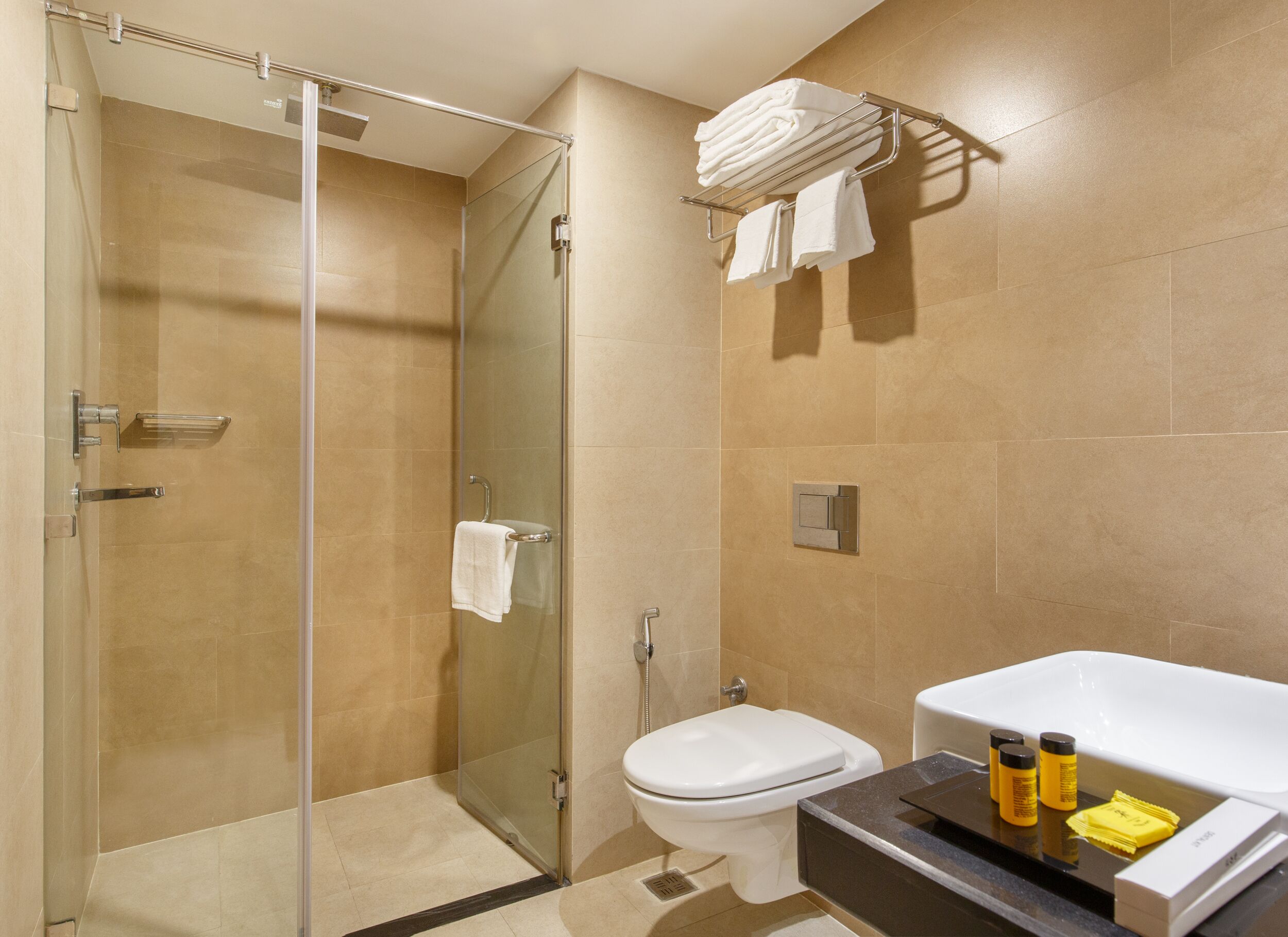 Un baño moderno con cabina de ducha de vidrio, inodoro y bañera con artículos de aseo.