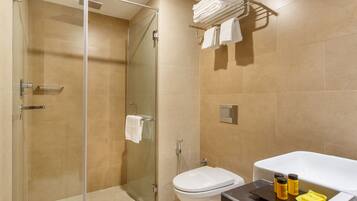 Un baño moderno con cabina de ducha de vidrio, inodoro y bañera con artículos de aseo.