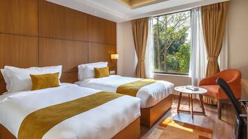 Habitación de hotel con dos camas, una mesita redonda pequeña, una silla y vistas a zonas verdes.