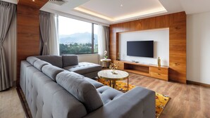 Una sala de estar moderna con un sofá modular, una mesa de centro redonda, un televisor de pantalla plana y un ventanal con vistas a la ciudad.