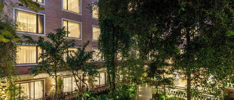 A multi-story building with large windows, a landscaped garden with a curved pathway, and a brick facade.