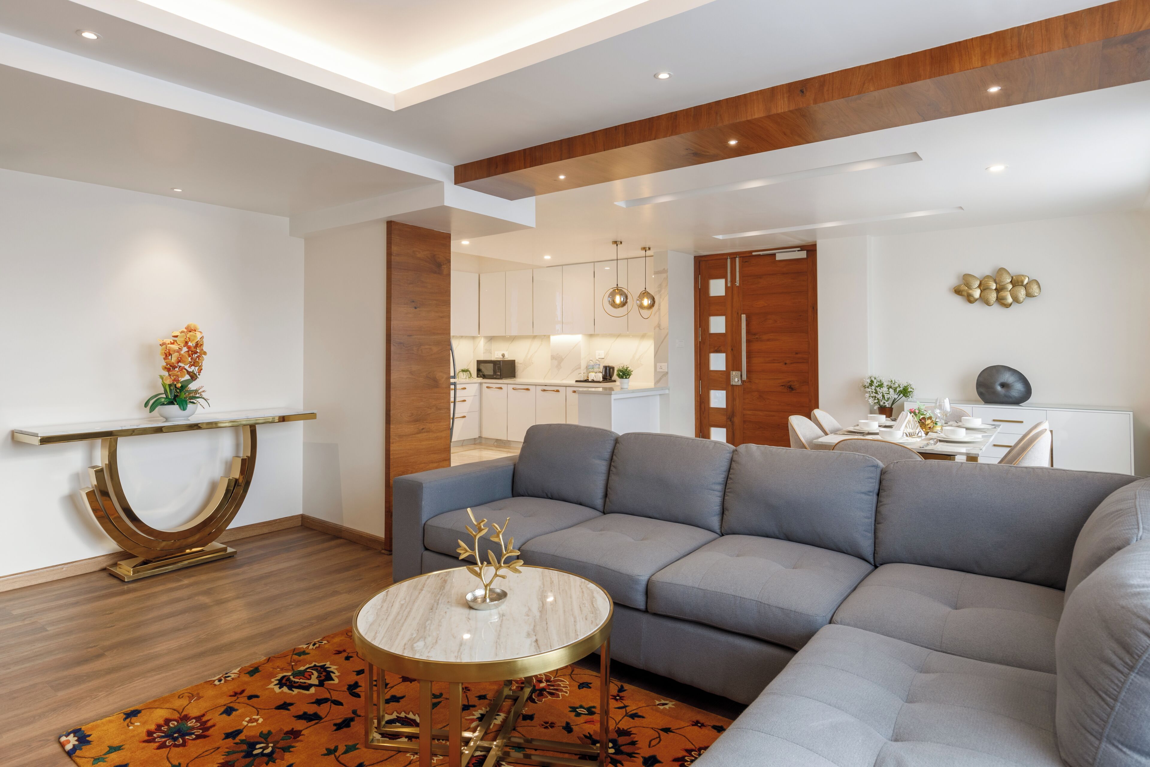 Una sala moderna con un sofá seccional gris, una mesita redonda y una consola decorativa.