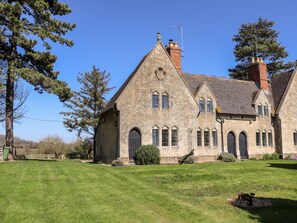 A stone building with a steeply pitched roof, multiple windows, and a chimney.
