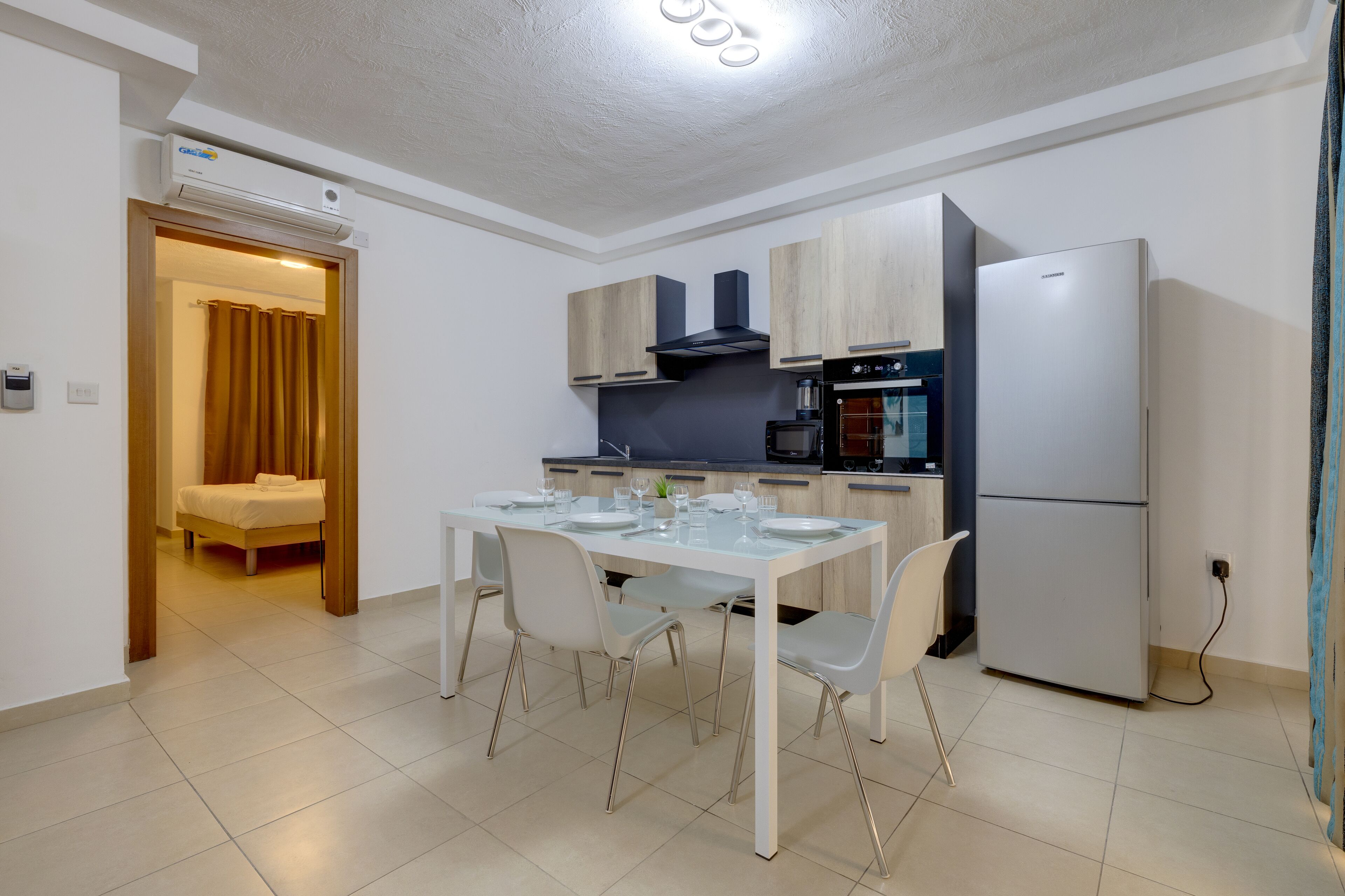 A modern kitchen with a dining table, chairs, and a refrigerator.