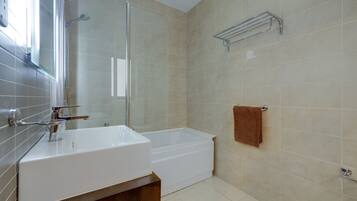 A modern bathroom with a white sink, bathtub, and glass shower enclosure.