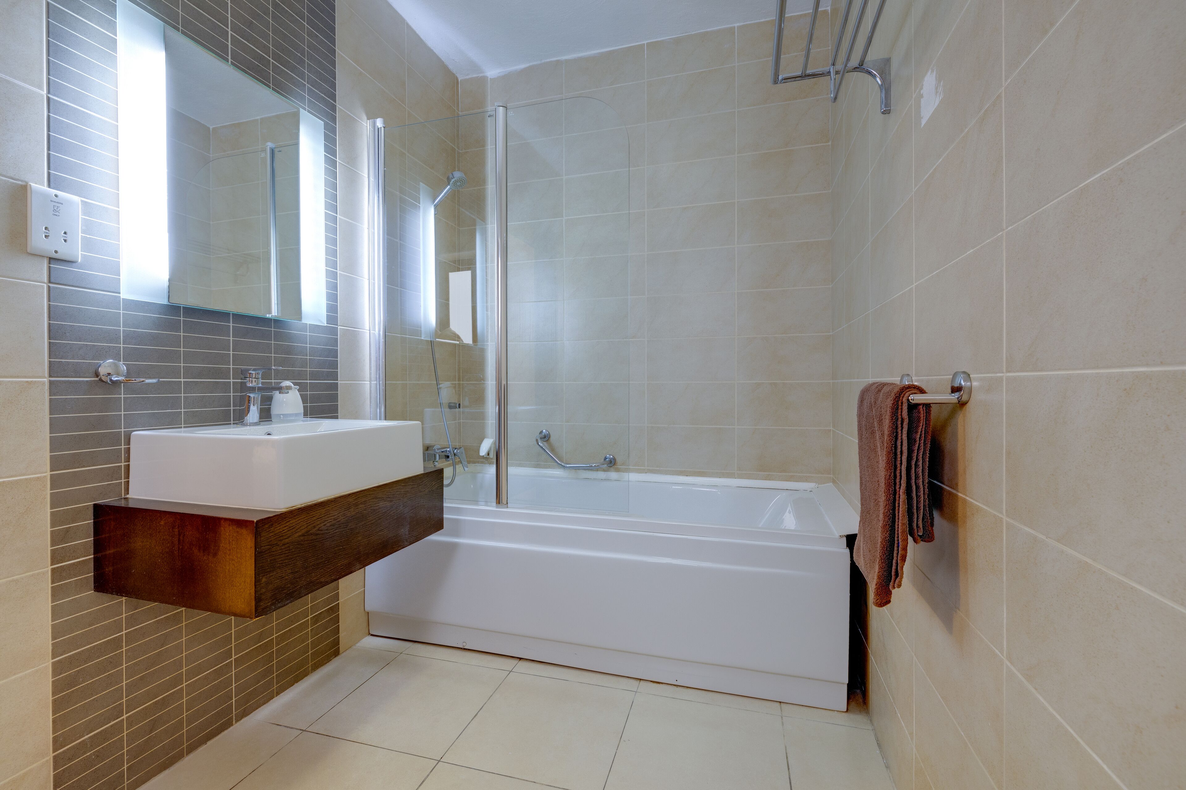 Un bany modern amb una banyera gran, un lavabo amb mirall i un escurapulides.