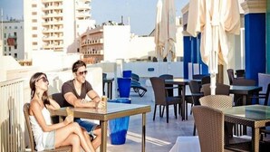 A rooftop terrace with outdoor seating, umbrellas, and a view of surrounding buildings. - Sliema Tigne Suites (Sliema)