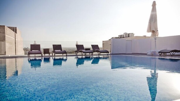 A rooftop pool with clear blue water, surrounded by lounge chairs and a white umbrella. - Sliema Tigne Suites (Sliema)